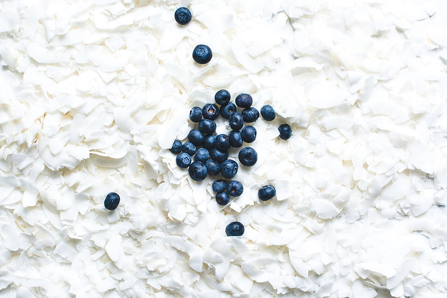 Fresh blueberries on white coconut flakes top view