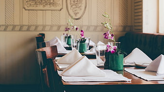 Elegant restaurant table setting with white napkins and orchids