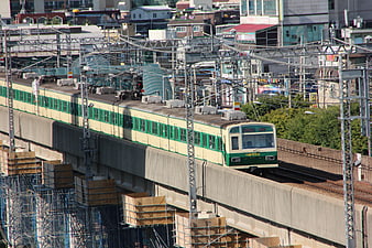 Green and cream commuter train on elevated urban tracks