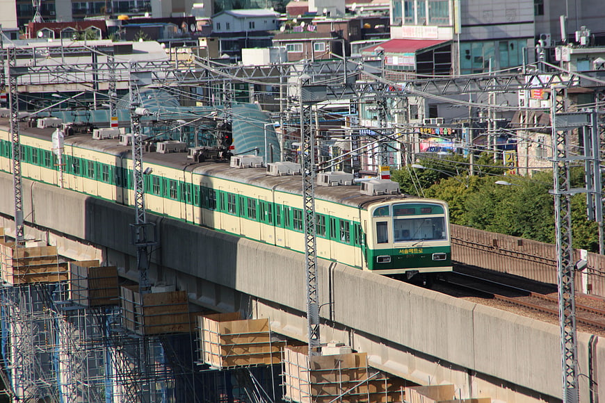 Green and cream commuter train on elevated urban tracks