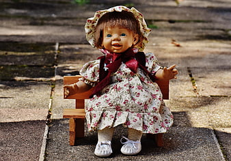 Vintage Doll in Floral Dress Sitting on Wooden Bench
