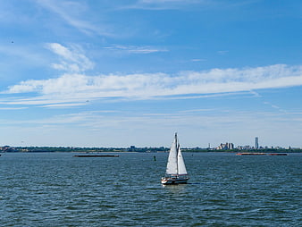 Sailboat on Blue Water with City Skyline Background