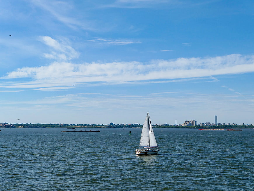 Sailboat on Blue Water with City Skyline Background