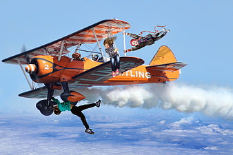 Aerial Stunt Performance With Children On Orange Biplane