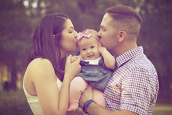 Parents kissing baby girl in park