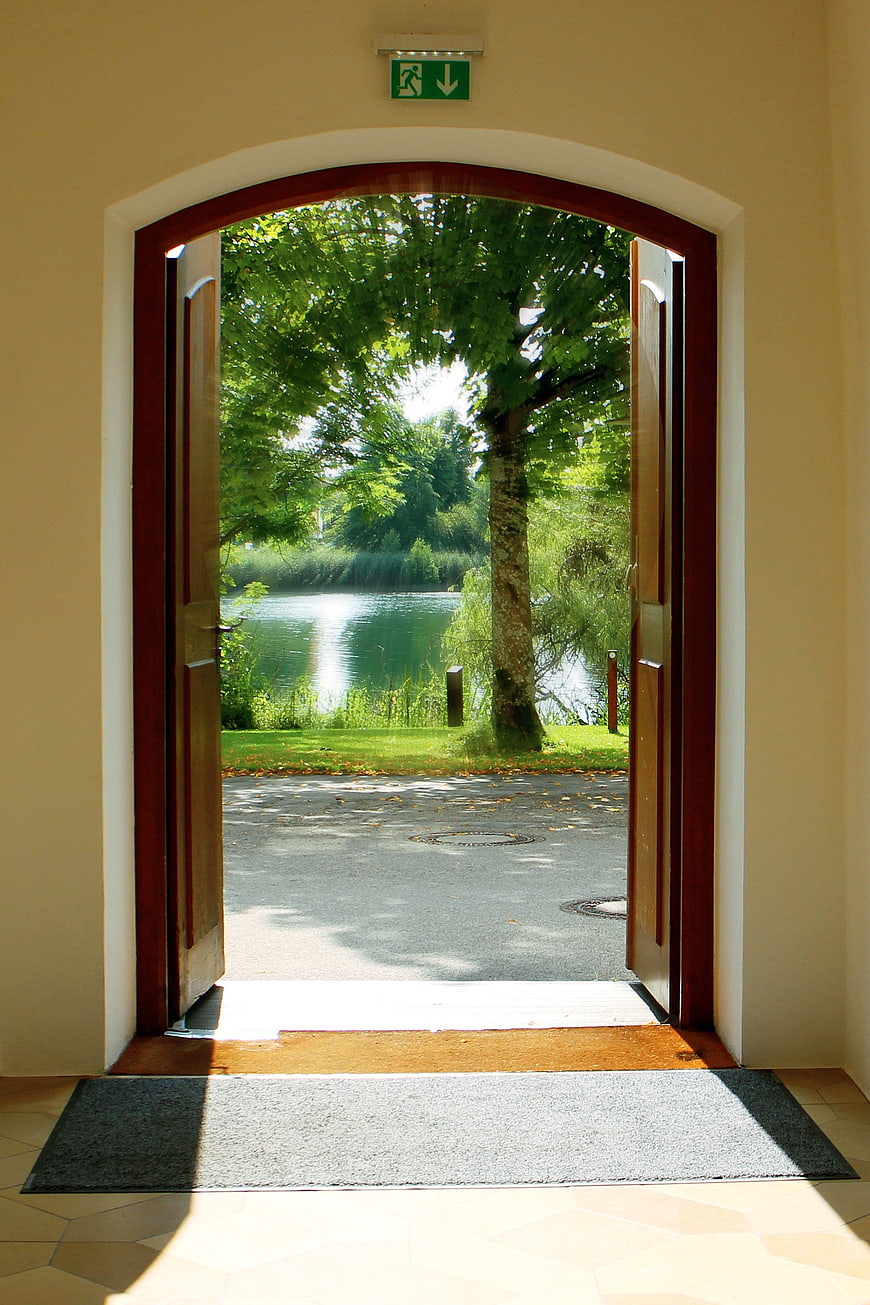 Open arched doorway revealing a sunny garden and lake view