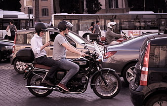 Two men riding motorcycle in city traffic