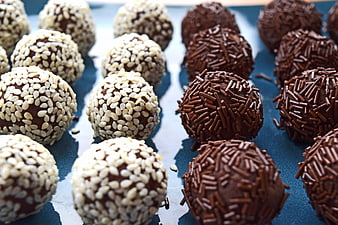 Chocolate truffles with sesame seeds and sprinkles on blue background