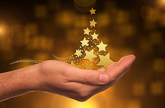 Hand holding glowing golden Christmas tree stars