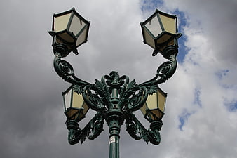 Vintage ornate green lamppost against cloudy sky