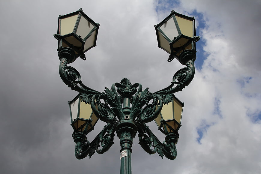 Vintage ornate green lamppost against cloudy sky