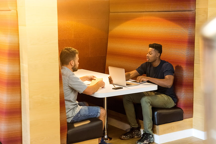 Two men collaborating in a modern office booth