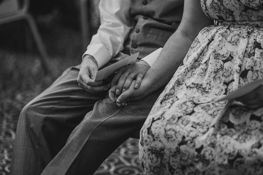 Black and white photo of couple holding hands with wedding programs
