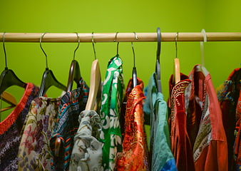 Colorful clothes hanging on a rack against a lime green wall