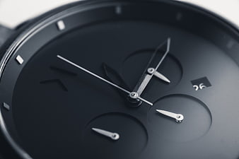 Close-up of a black chronograph watch face with silver hands