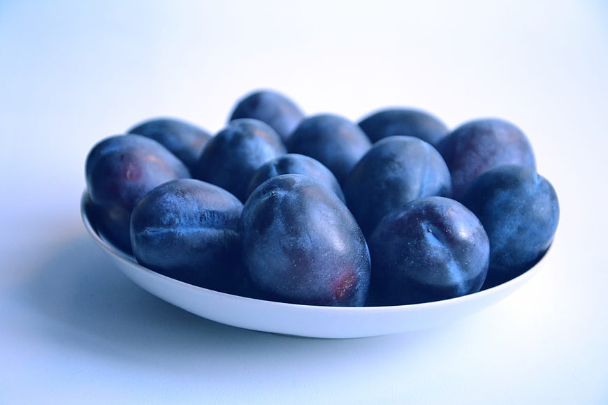Fresh Blue Plums in White Bowl on Clean Background