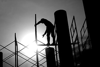 Silhouette of Construction Worker on Scaffolding Against Sun