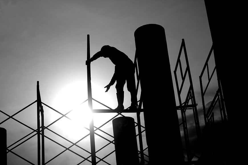 Silhouette of Construction Worker on Scaffolding Against Sun