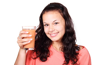 Young woman smiling while holding a glass of orange juice