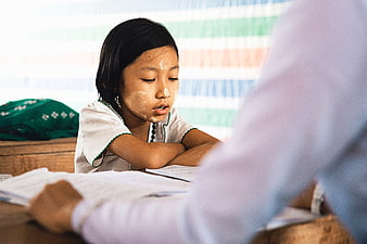 Young girl studying in school uniform with traditional face paste