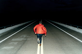 Man in Red Jacket Running on Dark Road at Night
