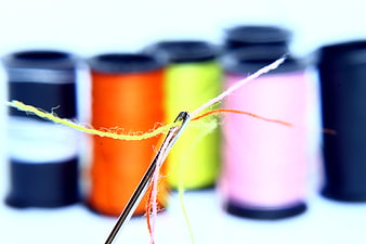 Close-up of a needle threaded with colorful yarn and thread