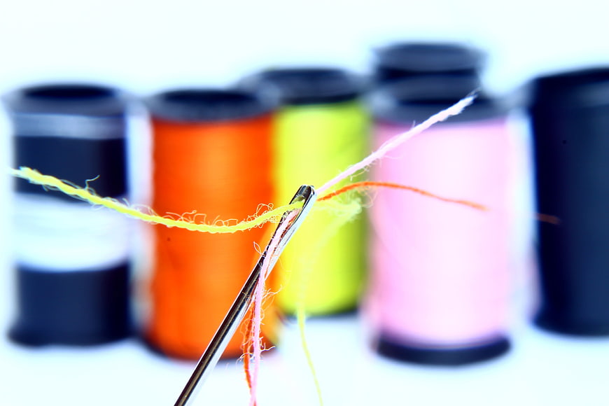 Close-up of a needle threaded with colorful yarn and thread