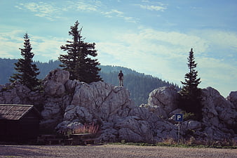 Man standing on rocky cliff overlooking forest mountains