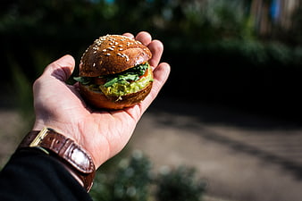 Hand holding mini burger with guacamole outdoors