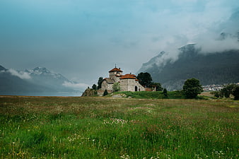 Historic stone church on a grassy hill with misty mountains