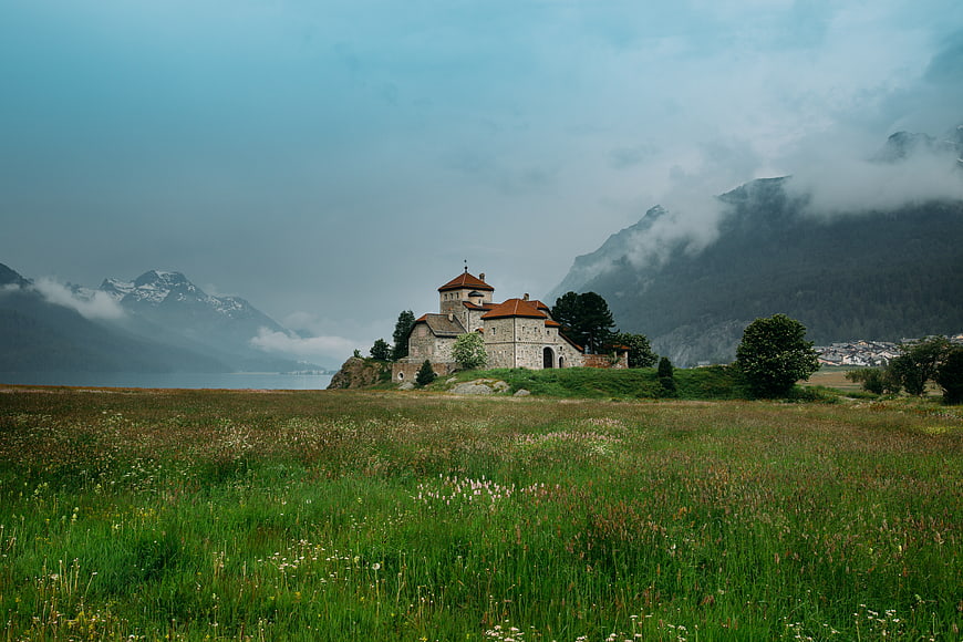 Historic stone church on a grassy hill with misty mountains