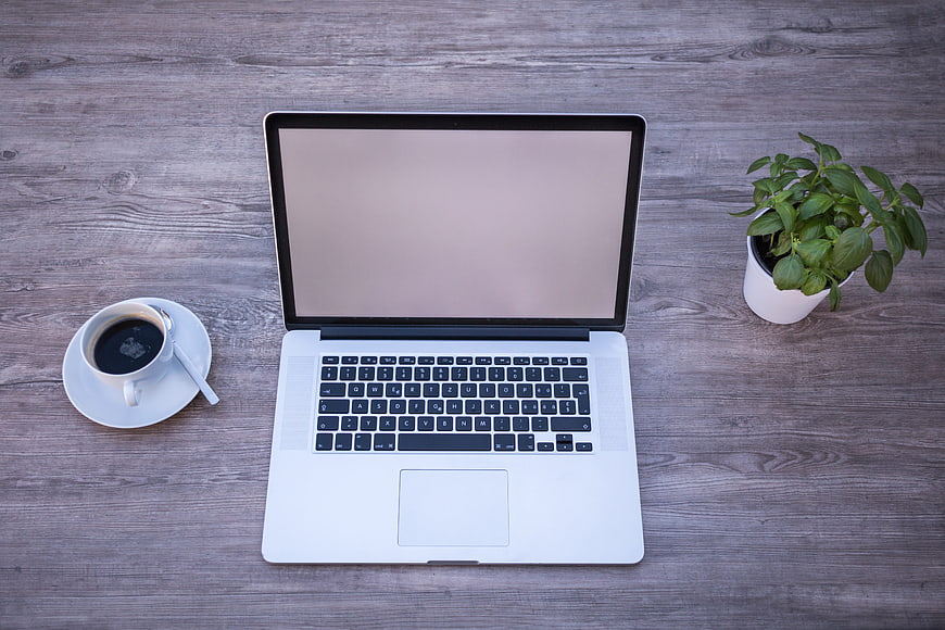 Top View Laptop Workspace with Coffee and Plant on Wooden Desk