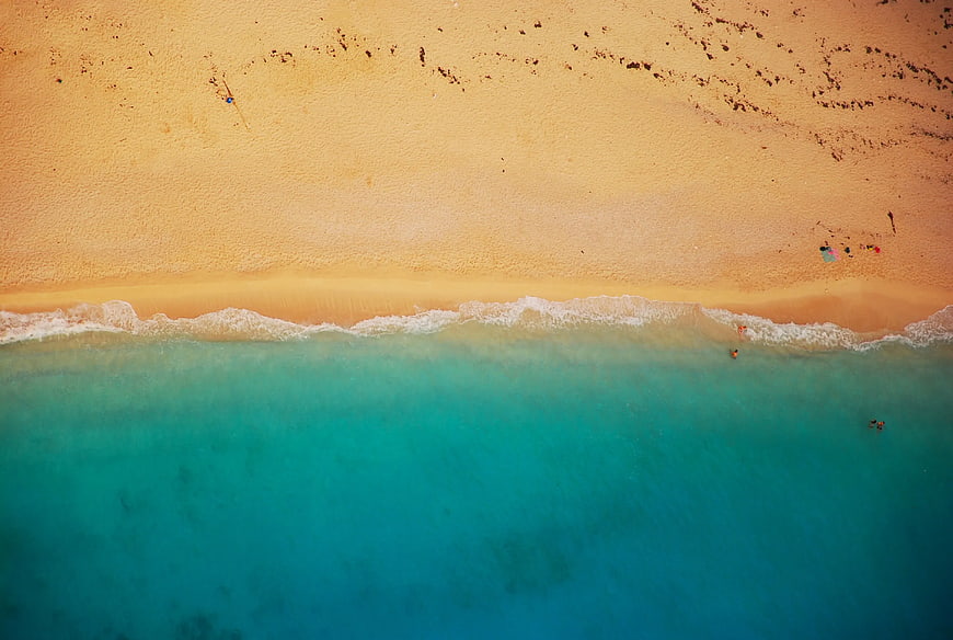 Aerial View of Turquoise Ocean Waves Meeting Sandy Beach