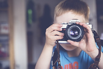 Young boy holding vintage Minolta camera to eye