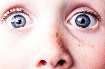 Close-up portrait of wide blue eyes and freckles