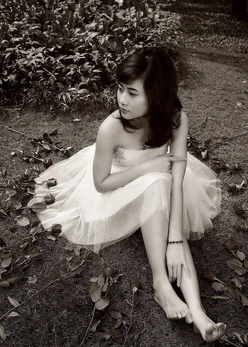 Woman in White Dress Sitting on Grass in Sepia Tone