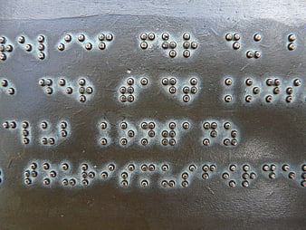 Close-up of raised braille dots on a textured metal plate