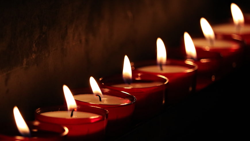 Row of burning red tea light candles in the dark