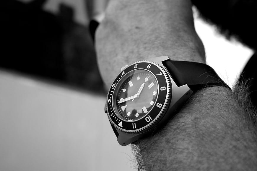 Close-up of black diver watch on hairy wrist in black and white
