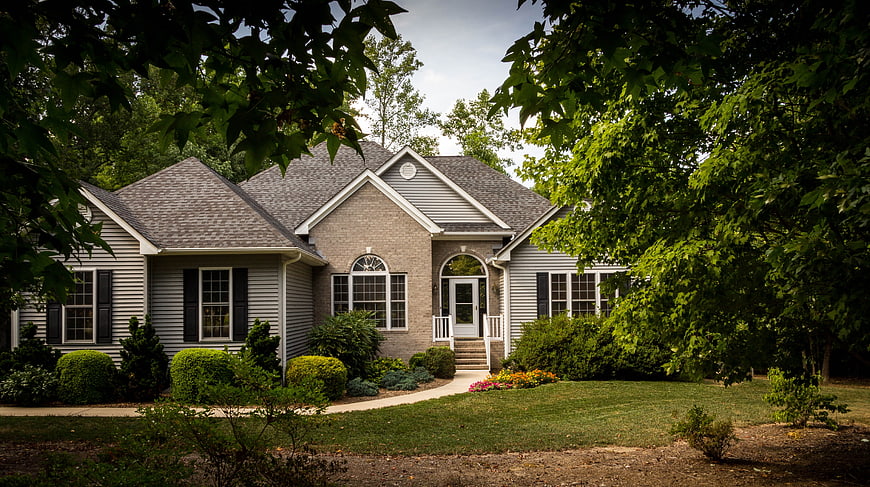 Suburban brick and siding home with lush green landscaping