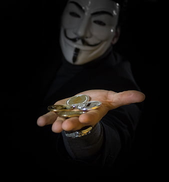 Anonymous Person in Guy Fawkes Mask Offering Cryptocurrency Coins