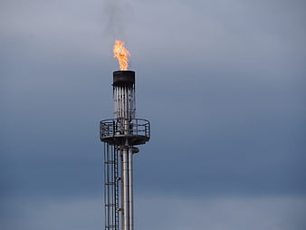 Industrial gas flare burning against overcast sky
