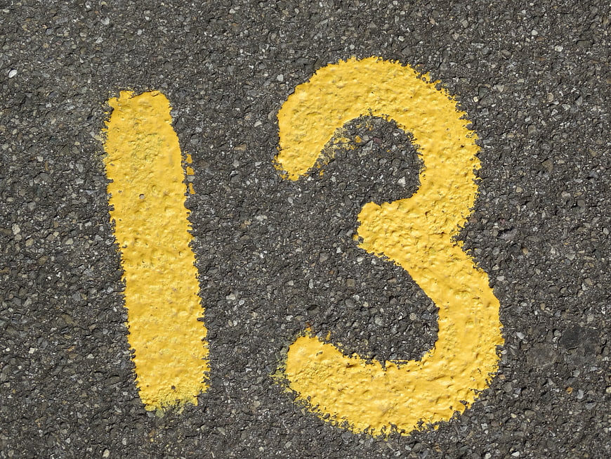 Yellow Number 13 Painted On Rough Asphalt Road Surface