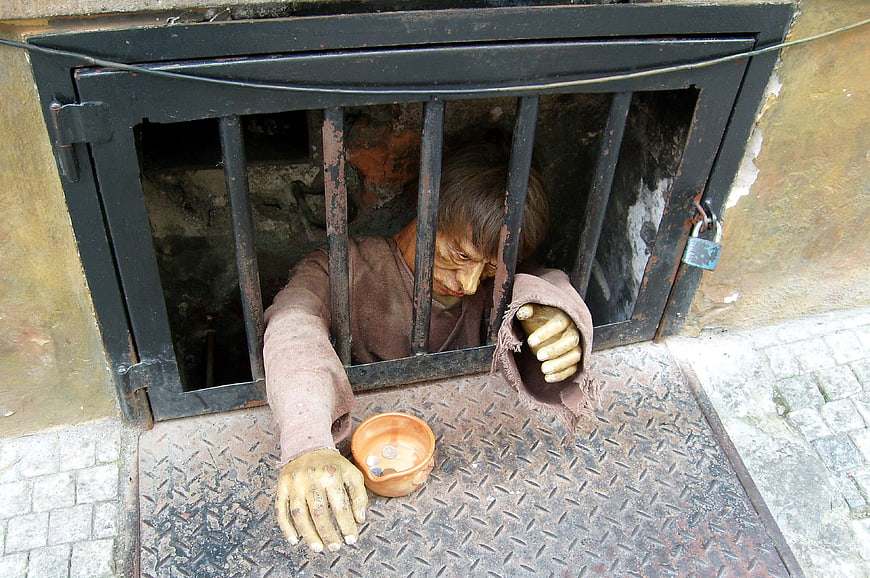 Gargoyle statue begging in Prague street grate