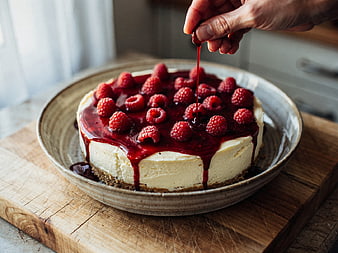 Hand Drizzling Raspberry Sauce on Cheesecake