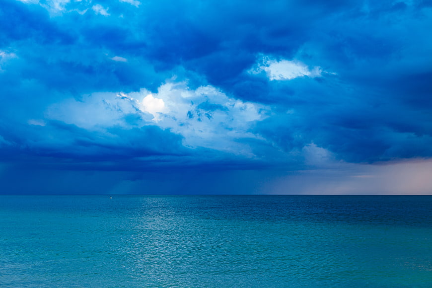 Dramatic Blue Stormy Sky Over Calm Ocean Horizon