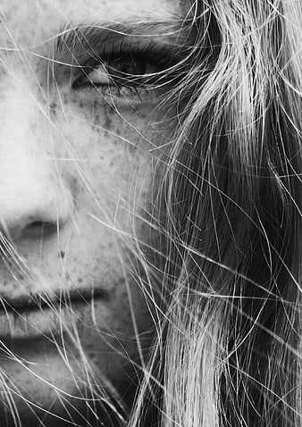 Close-up black and white portrait of woman with freckles and hair