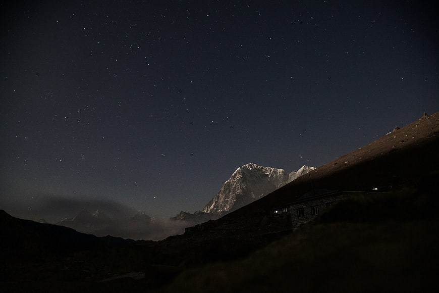 Starry Night Sky Over Snow-Capped Mountain Peak