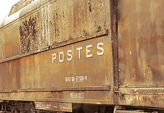 Rusty vintage mail train wagon with POSTES lettering in a train cemetery