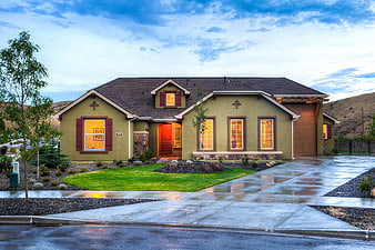 Modern suburban home exterior with wet driveway and warm lighting